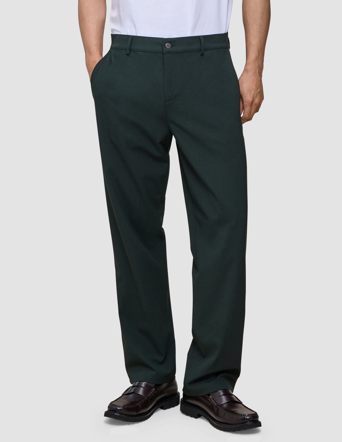 Person, die eine dunkelgrüne Ease-Hose in Relaxed Fit mit dem Muster Northern Pine und braune Loafer trägt.